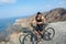 An attractive young woman dressed in black looks at her black bike on a summer day. Healthy Lifestyle