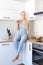 Attractive young woman drinking homemade fruit juice sitting on kitchen counter. Young housewife relaxing in the kitchen.