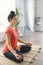 Attractive young woman exercising and sitting in yoga lotus position while resting at home