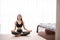 Attractive young woman exercising and sitting in yoga lotus position while resting at home