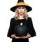 Attractive young woman in Halloween Witch costume holding large black pumpkin, looking confused. Halloween concept.