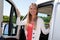 Attractive young woman in her camper van poses proudly behind the wheel of her motorhome