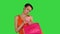 Attractive young woman holding different blank shopping bags making selfie on a green screen, chroma key.
