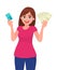 Attractive young woman holding or showing a credit/debit card and cash/money/currency notes in hand. Wireless modern bank payment.