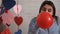 Attractive young woman inflates balloons at home preparing for the holiday, Valentine`s Day