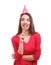 Attractive young woman with lollipop and party hat on white background