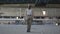 Attractive young woman in military uniform walking slowly in dusty dirty abandoned building carrying high-heeled shoes