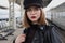 Attractive young woman millenial in black clothes and a hat and glasses at the railway station next to the train