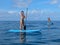 Attractive young woman paddling on SUP board on the tropical beach. Active summer vacations with paddle board. Beautiful Tropical