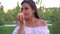 Attractive young woman with peach fruit outdoors. Woman is eating a ripe peach