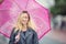 Attractive young woman with pink umbrella in the rain and strong wind. Girl with umbrella in autumn weather