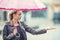 Attractive young woman with pink umbrella in the rain and strong wind. Girl with umbrella in autumn weather