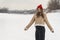 Attractive young woman in red knitted hat and beige sheepskin coat. Walking through winter snow-covered park