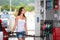 Attractive, young woman refueling her car in a gas station