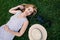 Attractive young woman rests lying on the grass in a park. He is accompanied by a hat and his camera