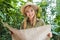 attractive young woman in safari suit with parrot on shoulder navigating in jungle