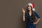 Attractive young woman Santa standing on brown background. Christmas holiday and New Year party