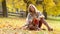 Attractive young woman with sensual smile sitting in autumn park. 4k video shot slow motion