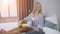 Attractive young woman in shirt having breakfast while sitting on bed with tray