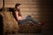 Attractive young woman in sporty dress in a barn posing with hay