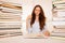 Attractive young woman studies wtih huge book piles on her desk