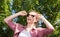 Attractive young woman in sunglasses posing in nature and clings to glasses hands