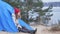 Attractive young woman tourist in a red hat sits in a tourist tent and drinks tea from a thermos