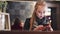 Attractive young woman using her mobile phone while sitting in the cafÃ©. Fashionable outlook, red lips, leather jacket