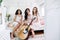Attractive young women of different ethnics with guitar have fun together posing inside the camper van