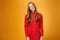 Attrative and stylish elegant busiensswoman with ginger hair in red knitted dress tilting head and smiling flirty and