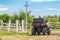 ATV quad bike vehicle standing near wooden fence at farm or horse stable. Back view of all wheel drive motorcycle at