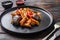 Aubergine penne eggplant pasta, pepper tomatoe sauce, on black plate over old dark wooden table served side view