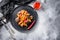 Aubergine penne eggplant pasta, pepper tomatoe sauce, on black plate overgrey concrete background  served top view space for text