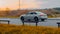 Audi A4 B9 driving on the country road at dusk. Side view of white sedan in motion on the background of autumn nature