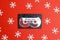 Audio cassette tape with decorative snowflakes on a red background. Music for Christmas mood.