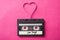 audio cassette with text `Love songs` with magnetic band in shaped heart on pink background
