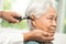 Audiologist or ENT doctor use otoscope checking ear of asian senior woman patient treating hearing loss problem