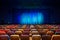 The auditorium in the theater. Blue-green curtain on the stage. Multicolored spectator chairs. Lighting equipment