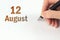 August 12nd. Day 12 of month, Calendar date. The hand holds a black pen and writes the calendar date. Summer month, day of the