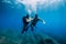 August 20, 2020. Anapa, Russia. Couple of scuba divers glides underwater in transparent blue sea. Scuba diving in clear ocean