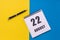 August 22th. Day of 22 month, calendar date. A notebook with a spiral and a pen lies on a yellow-blue background, flat lay, copy