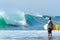 August 26 2014: Bali, Indonesia. Nice wave breaking with man standing on the reef waiting to paddle out