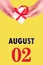 August 2nd. Festive Vertical Calendar With Hands Holding White Gift Box With Red Ribbon And Calendar Date