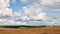 August landscape. Large cumulus clouds in the blue sky over a freshly mown field