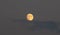 August orange full moon hides behind blue clouds background, texture