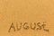 August - word inscription on the gold sand beach.