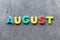 August word written with colorful letters on grey granite stone background