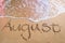 August written on beach sand