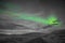 Aurora Borealis in Iceland northern lights bright beams rising green over black and white scenery