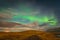 Aurora Borealis in Iceland northern lights bright beams rising green over hiking path